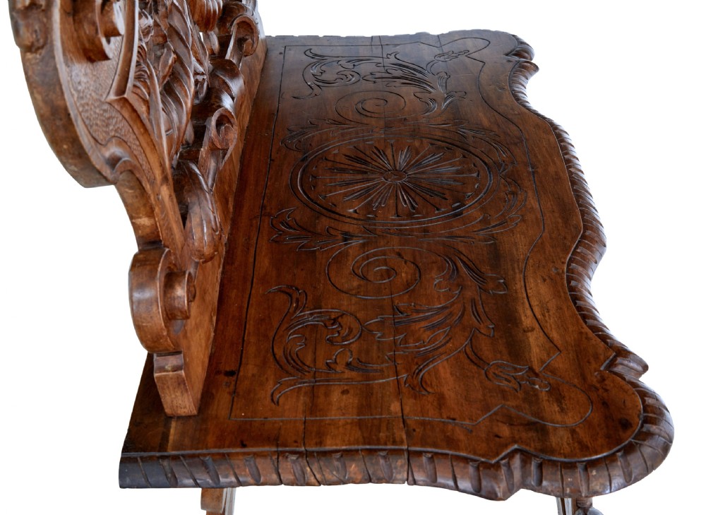 A 19th-century Flemish walnut hall chair decorated with openwork carvings of grotesque masks, cherubs blowing trumpets, and a central shield motif. View X