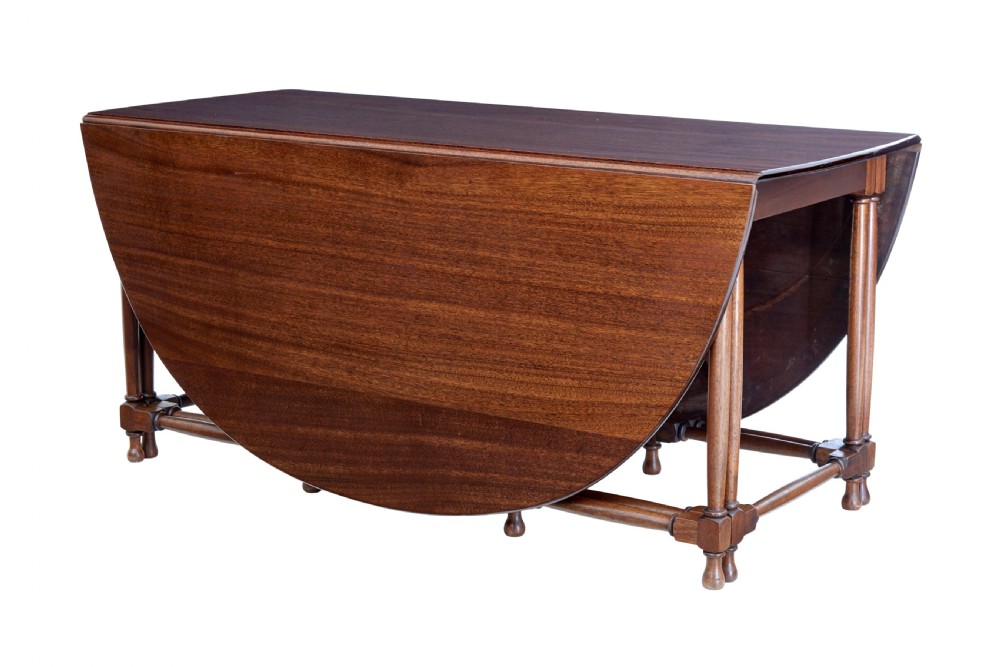 An early 20th-century mahogany gateleg dining table shown with both drop-down leaves folded against turned wooden legs.