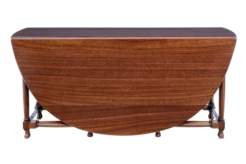 An early 20th-century mahogany gateleg dining table shown with both drop-down leaves folded against turned wooden legs. View II