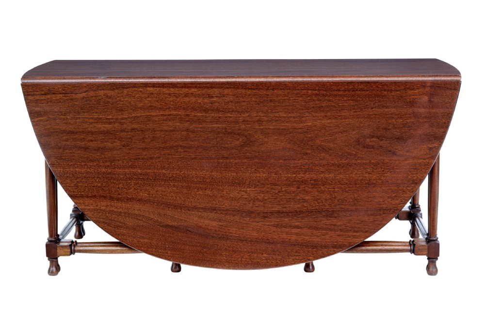 An early 20th-century mahogany gateleg dining table shown with both drop-down leaves folded against turned wooden legs. View III