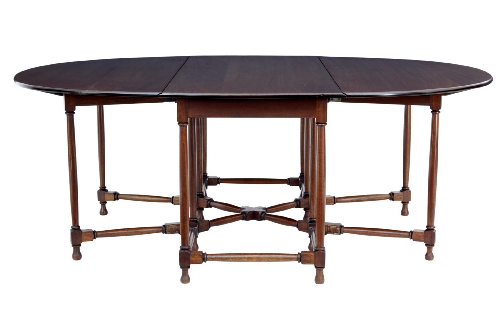 An early 20th-century mahogany gateleg dining table shown with both drop-down leaves folded against turned wooden legs. View V