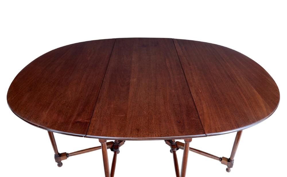 An early 20th-century mahogany gateleg dining table shown with both drop-down leaves folded against turned wooden legs. View VI