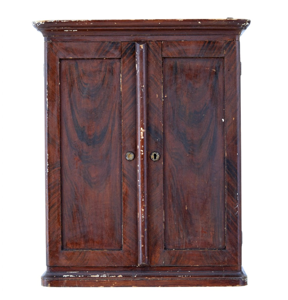 A 19th-century Scandinavian wall cabinet featuring a dark reddish-brown faux-grained paint finish, two panelled doors with brass keyholes, and a moulded top cornice. View II