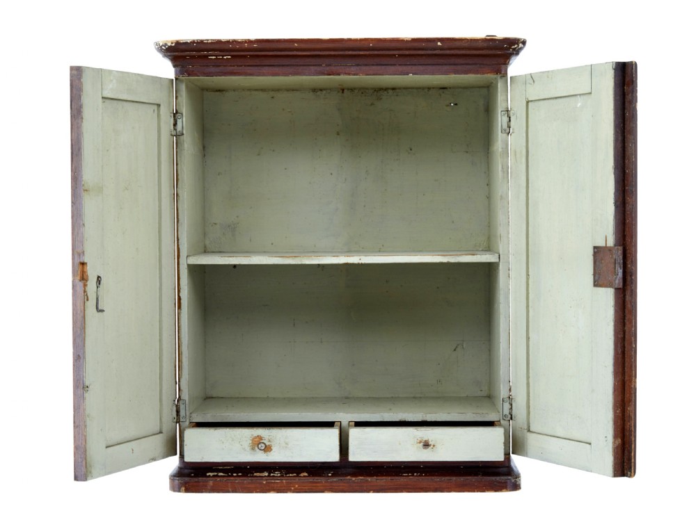 A 19th-century Scandinavian wall cabinet featuring a dark reddish-brown faux-grained paint finish, two panelled doors with brass keyholes, and a moulded top cornice. View III