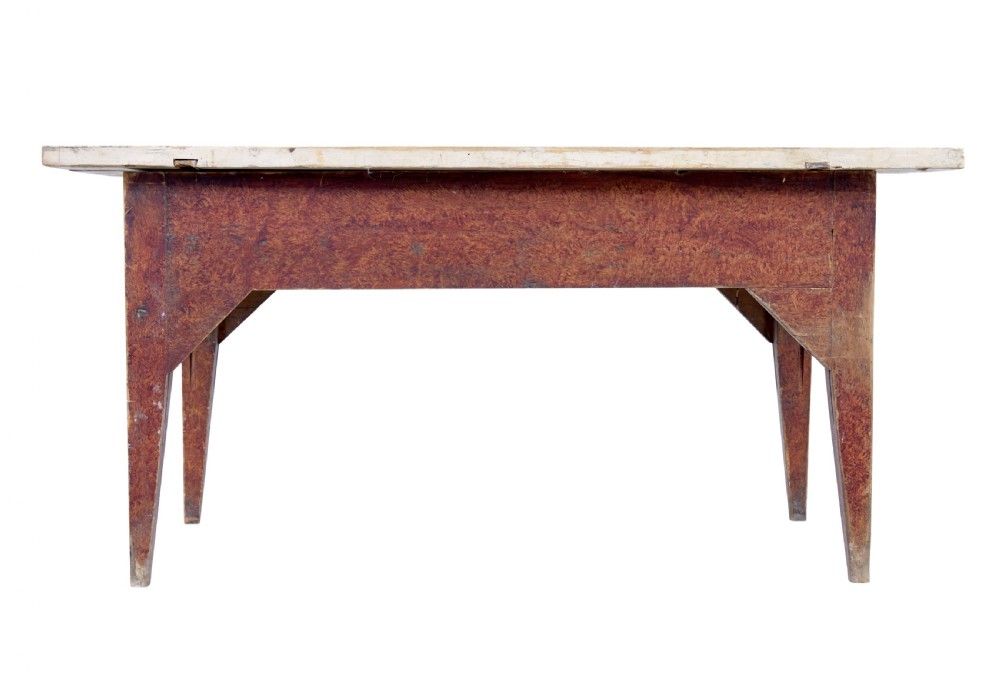 A mid 19th-century rustic pine kitchen table featuring a light wood top, a painted reddish-brown apron, and four tapered square legs.