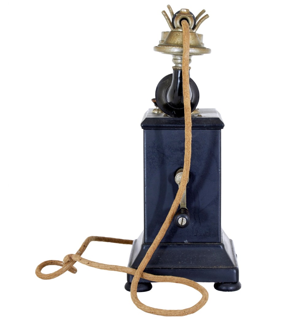 An early twentieth-century black metal Swedish Rikstelefon tabletop telephone with a brass handset cradle, fabric cord, side hand crank, and central blue crown decal. View III
