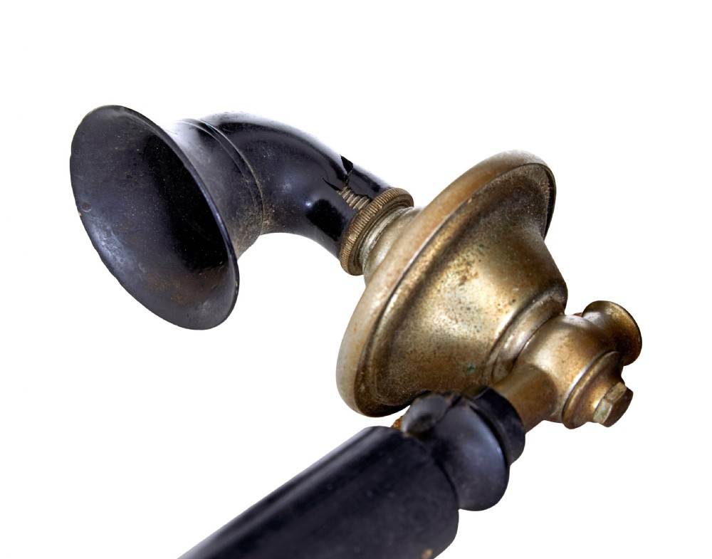 An early twentieth-century black metal Swedish Rikstelefon tabletop telephone with a brass handset cradle, fabric cord, side hand crank, and central blue crown decal. View VI