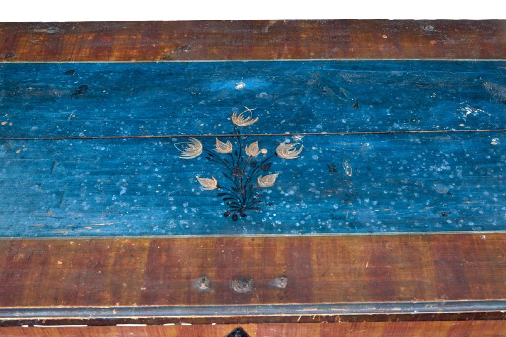 A mid-19th-century Swedish painted wooden coffer featuring blue centre panels decorated with a floral wreath and the date 1855, framed by terracotta borders and black wrought iron straps. View VII