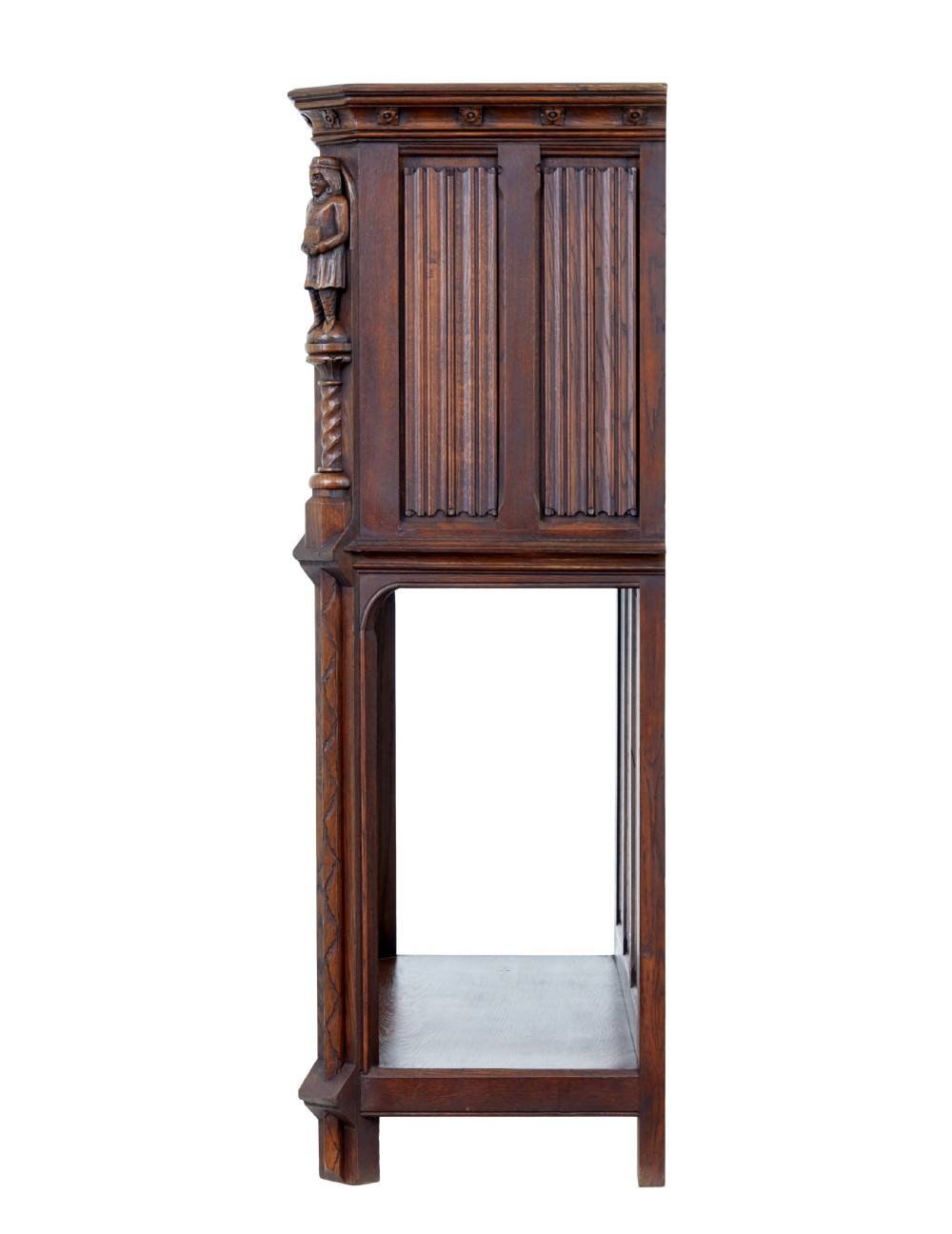 A dark oak Renaissance Revival cupboard featuring carved human figures, gothic arched panels, iron hardware, and an open lower shelf. View IV