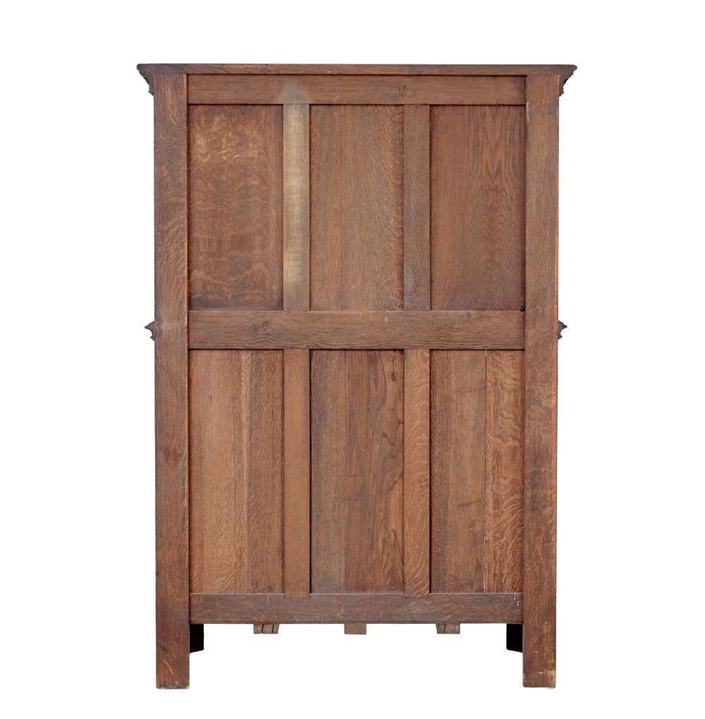 A dark oak Renaissance Revival cupboard featuring carved human figures, gothic arched panels, iron hardware, and an open lower shelf. View V