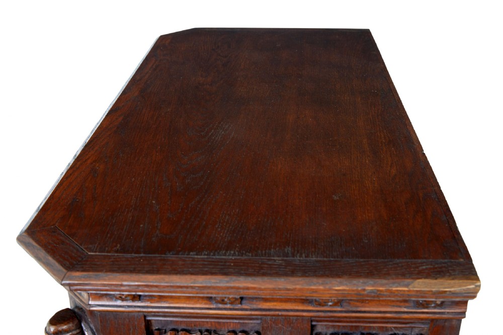 A dark oak Renaissance Revival cupboard featuring carved human figures, gothic arched panels, iron hardware, and an open lower shelf. View IX