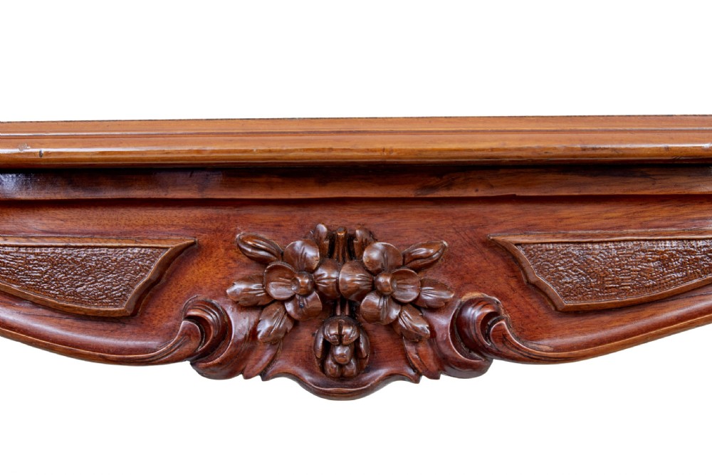A 19th-century carved walnut occasional table featuring a shaped burr walnut top, ornate floral apron, cabriole legs, and a carved central stretcher finial on castors. View VII