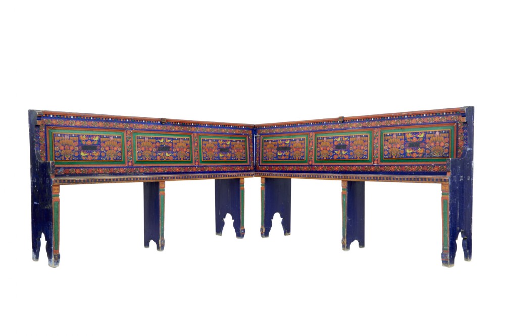 A nineteenth-century L-shaped wooden corner bench featuring hand-painted floral panels in red, green, and orange over a deep blue frame.