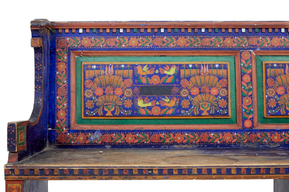A nineteenth-century L-shaped wooden corner bench featuring hand-painted floral panels in red, green, and orange over a deep blue frame. View VI