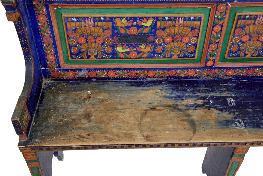 A nineteenth-century L-shaped wooden corner bench featuring hand-painted floral panels in red, green, and orange over a deep blue frame. View VII