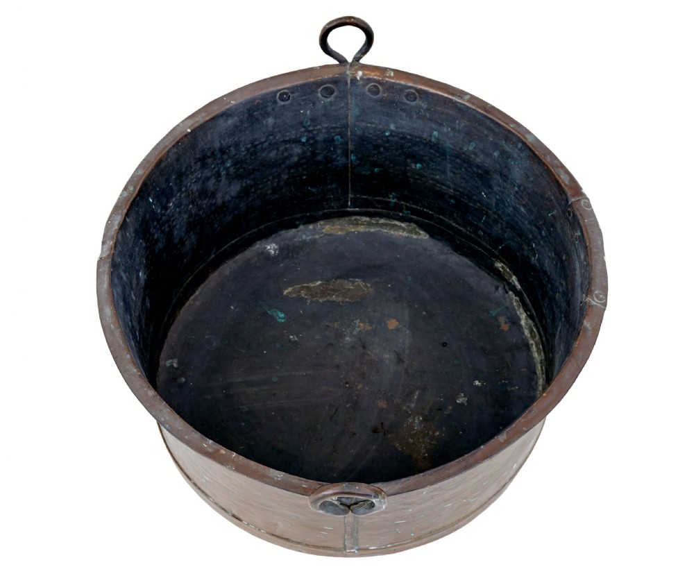 A large, circular nineteenth-century copper vessel with deep sides, hand-riveted seams, and two upright loop handles. View IV