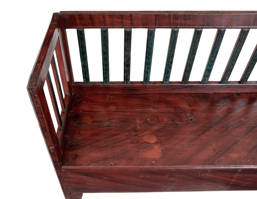 A mid 19th-century Swedish rustic pine bench featuring a dark red painted finish, a spindle backrest with contrasting dark green slats, and an enclosed box base. View III