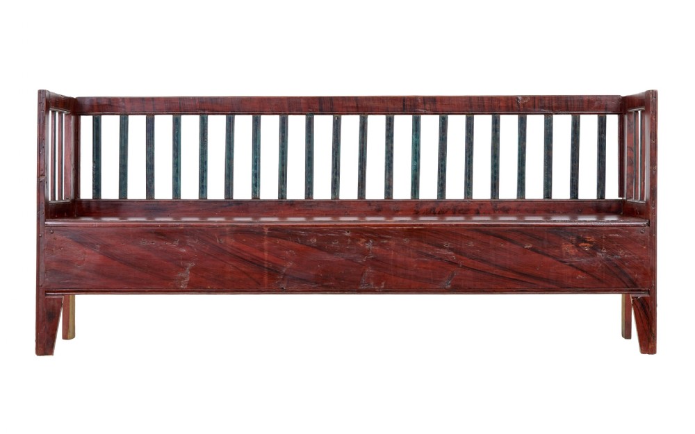 A mid 19th-century Swedish rustic pine bench featuring a dark red painted finish, a spindle backrest with contrasting dark green slats, and an enclosed box base. View V