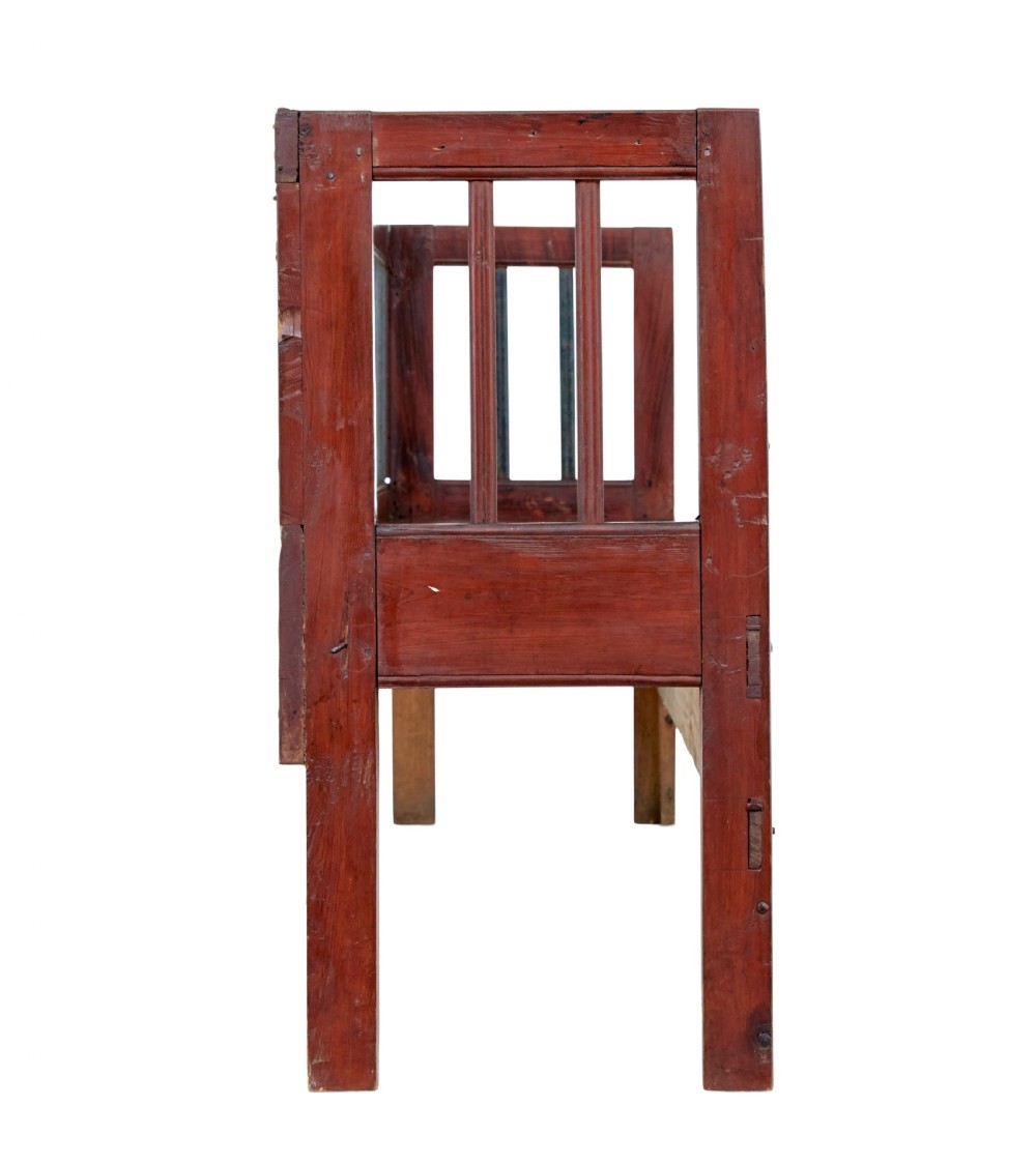 A mid 19th-century Swedish rustic pine bench featuring a dark red painted finish, a spindle backrest with contrasting dark green slats, and an enclosed box base. View VII