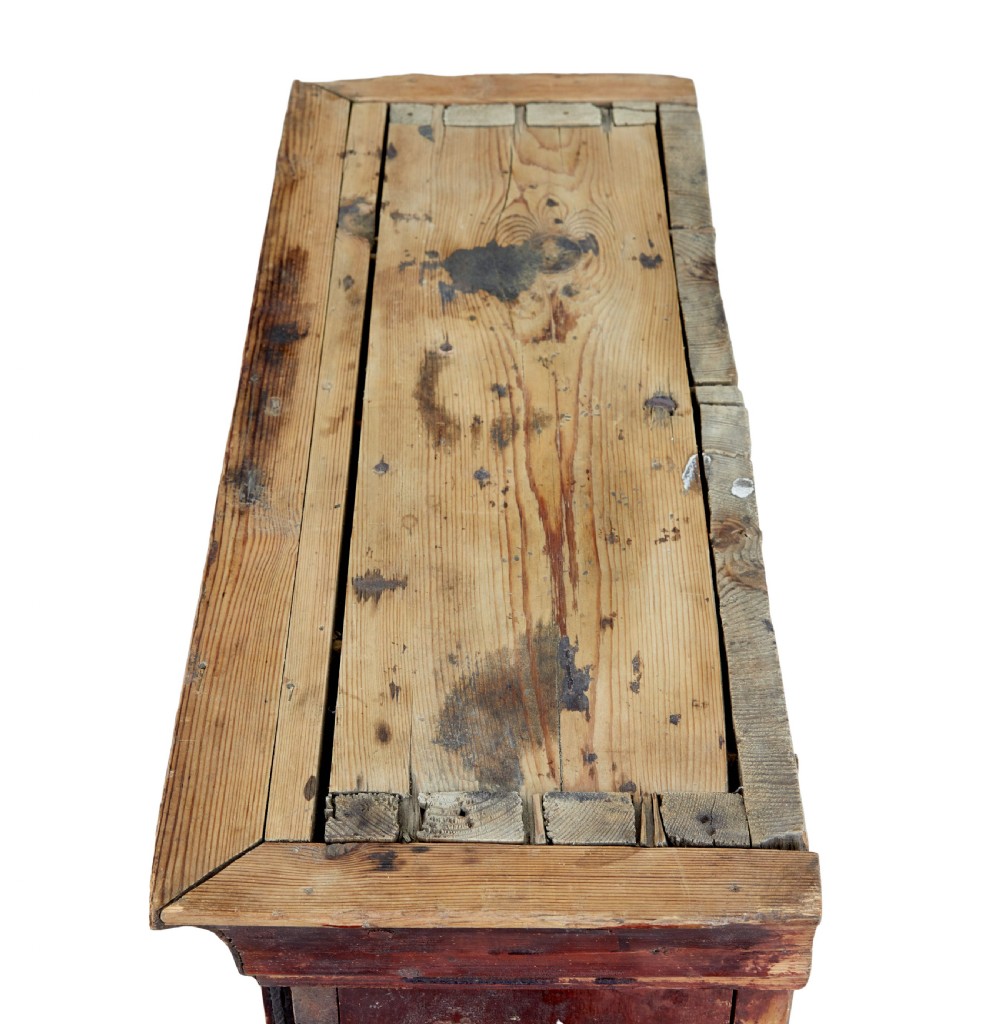 An early 19th-century Swedish painted pine wall cupboard featuring double panelled doors in a terracotta finish with moulded borders and central iron lock plate. View V