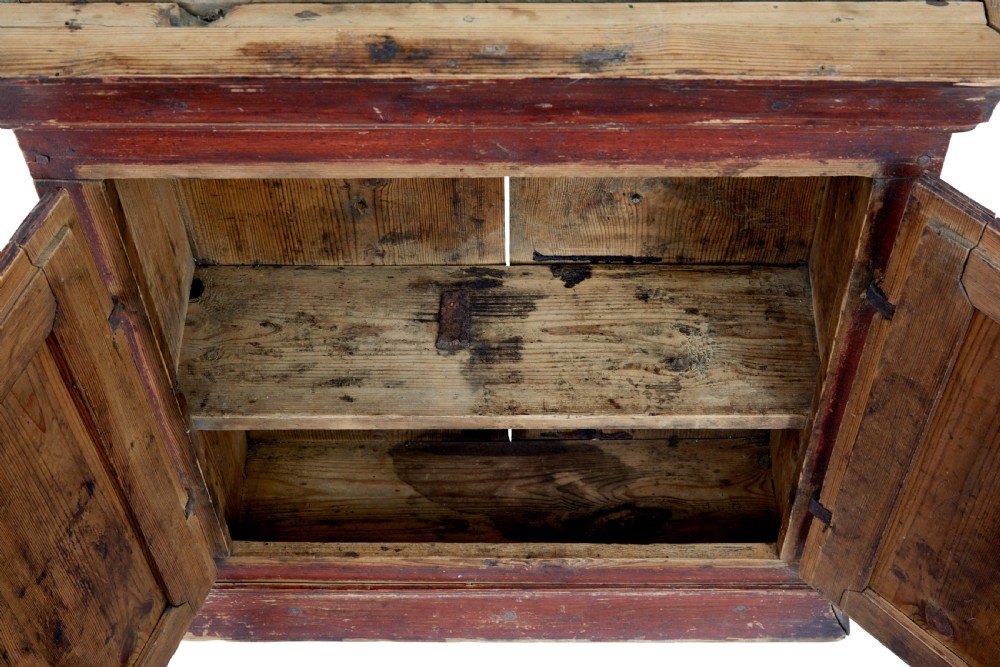 An early 19th-century Swedish painted pine wall cupboard featuring double panelled doors in a terracotta finish with moulded borders and central iron lock plate. View VI