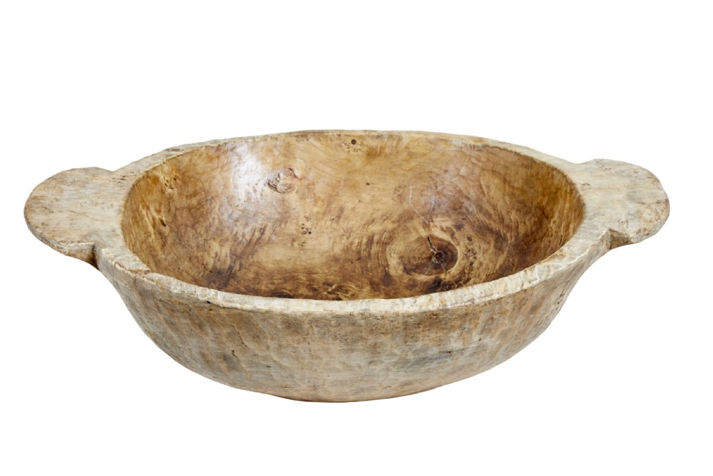 A large hand-carved rustic wooden bowl featuring side handles, hand-hewn tool marks, and natural timber grain.