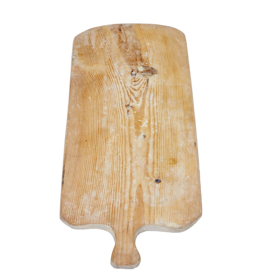 A long rectangular pale pine breadboard featuring a shaped handle at one end and natural timber grain with a knot. View III