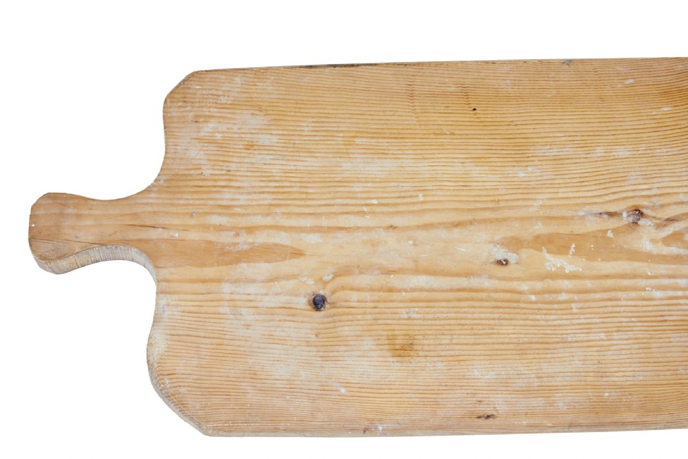 A long rectangular pale pine breadboard featuring a shaped handle at one end and natural timber grain with a knot. View V