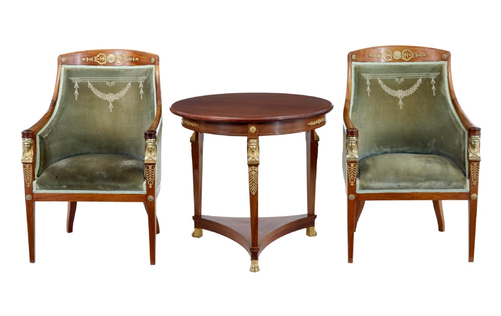 A three-piece Swedish Empire revival suite comprising two mahogany armchairs upholstered in green velvet with embroidered swag motifs and ormolu mounts alongside a matching round centre table with a triform base.