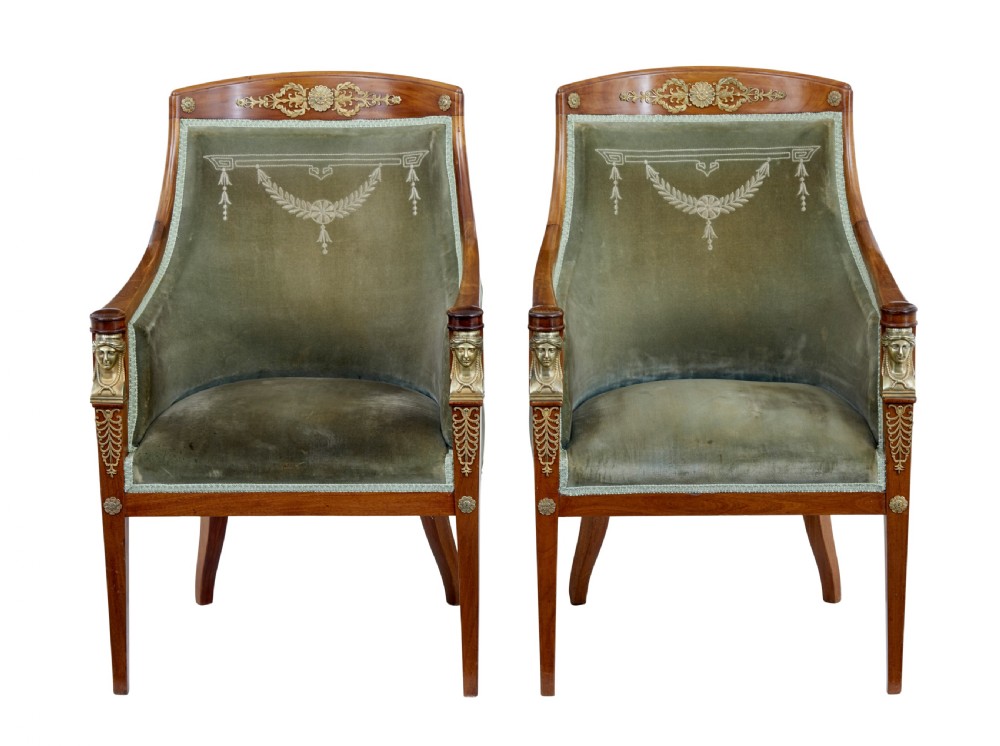 A three-piece Swedish Empire revival suite comprising two mahogany armchairs upholstered in green velvet with embroidered swag motifs and ormolu mounts alongside a matching round centre table with a triform base. View II