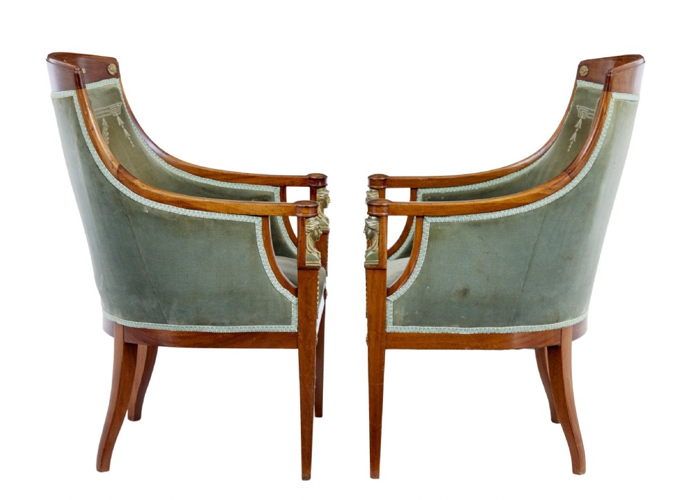 A three-piece Swedish Empire revival suite comprising two mahogany armchairs upholstered in green velvet with embroidered swag motifs and ormolu mounts alongside a matching round centre table with a triform base. View V