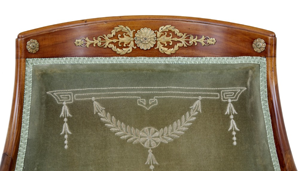 A three-piece Swedish Empire revival suite comprising two mahogany armchairs upholstered in green velvet with embroidered swag motifs and ormolu mounts alongside a matching round centre table with a triform base. View VI