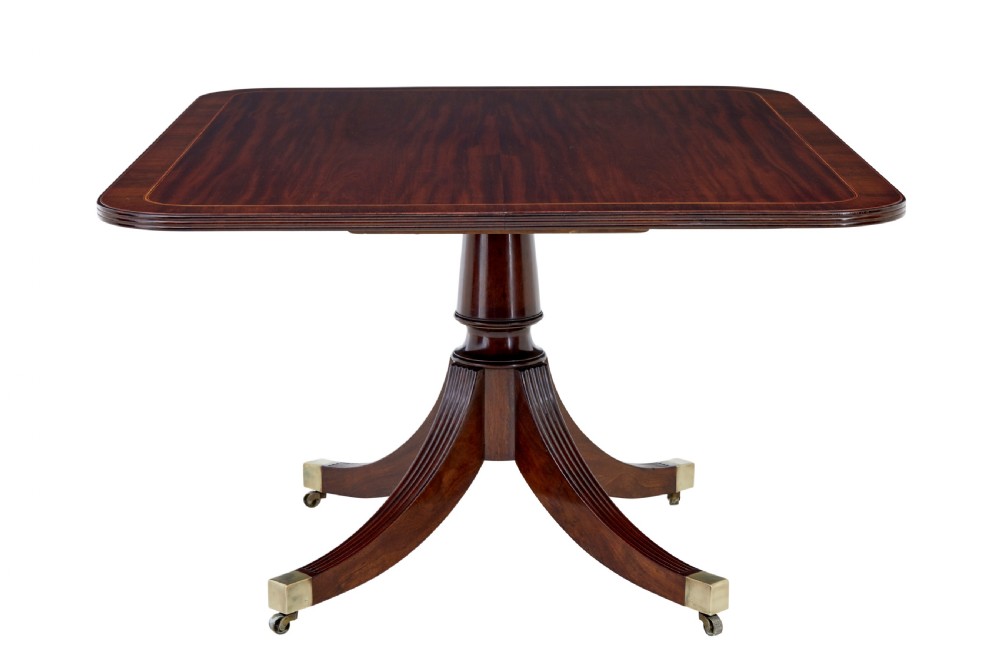 An early 19th-century Regency mahogany breakfast table featuring an inlaid rectangular top with rounded corners, supported by a turned pedestal and four reeded legs with brass castors. View II