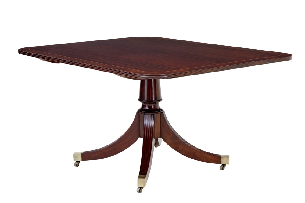 An early 19th-century Regency mahogany breakfast table featuring an inlaid rectangular top with rounded corners, supported by a turned pedestal and four reeded legs with brass castors. View III