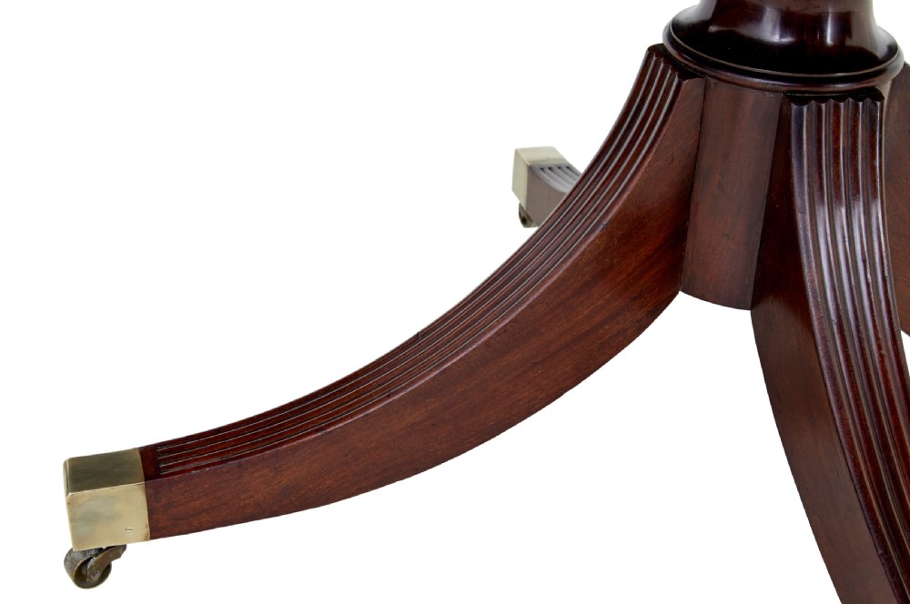 An early 19th-century Regency mahogany breakfast table featuring an inlaid rectangular top with rounded corners, supported by a turned pedestal and four reeded legs with brass castors. View IV