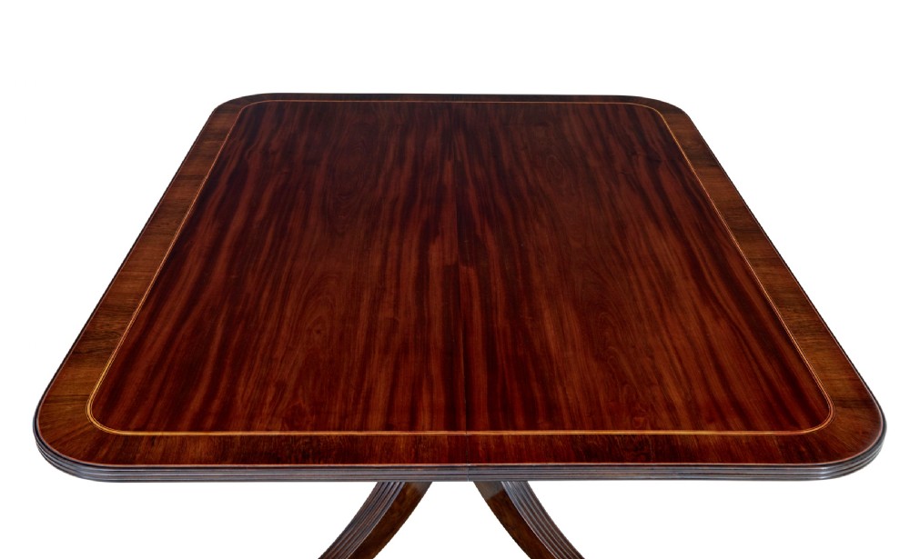 An early 19th-century Regency mahogany breakfast table featuring an inlaid rectangular top with rounded corners, supported by a turned pedestal and four reeded legs with brass castors. View VI