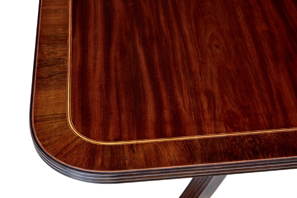 An early 19th-century Regency mahogany breakfast table featuring an inlaid rectangular top with rounded corners, supported by a turned pedestal and four reeded legs with brass castors. View VII