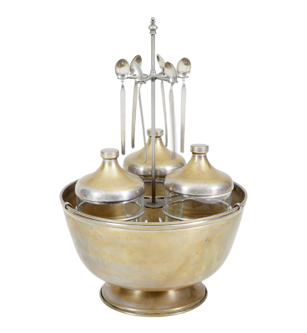 An early 20th-century Scandinavian metal and glass caviar ice server set featuring a central bowl, three lidded glass jars, and suspended spoons.