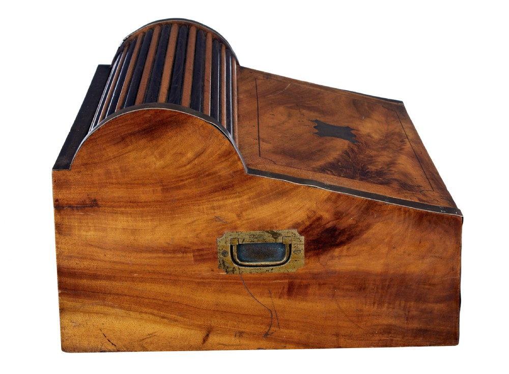 A mid-nineteenth century camphorwood campaign lap desk featuring a curved tambour roll top, sloped front, and recessed brass handles. View VI