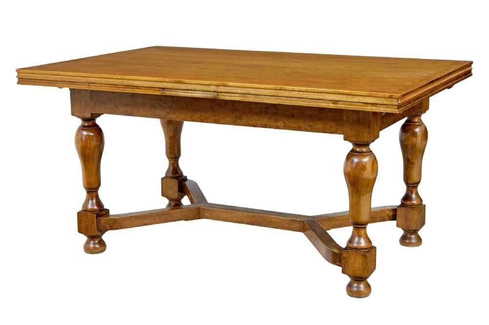 An early 20th-century birch extending dining table with a rectangular top, turned baluster legs, and a low central stretcher base.