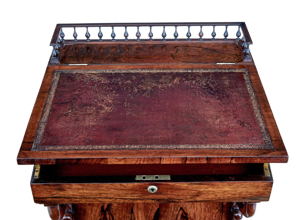 A 19th-century Regency palisander Davenport desk featuring a sloped leather writing top, carved scroll brackets, side drawers, and a brass spindle top gallery. View IV
