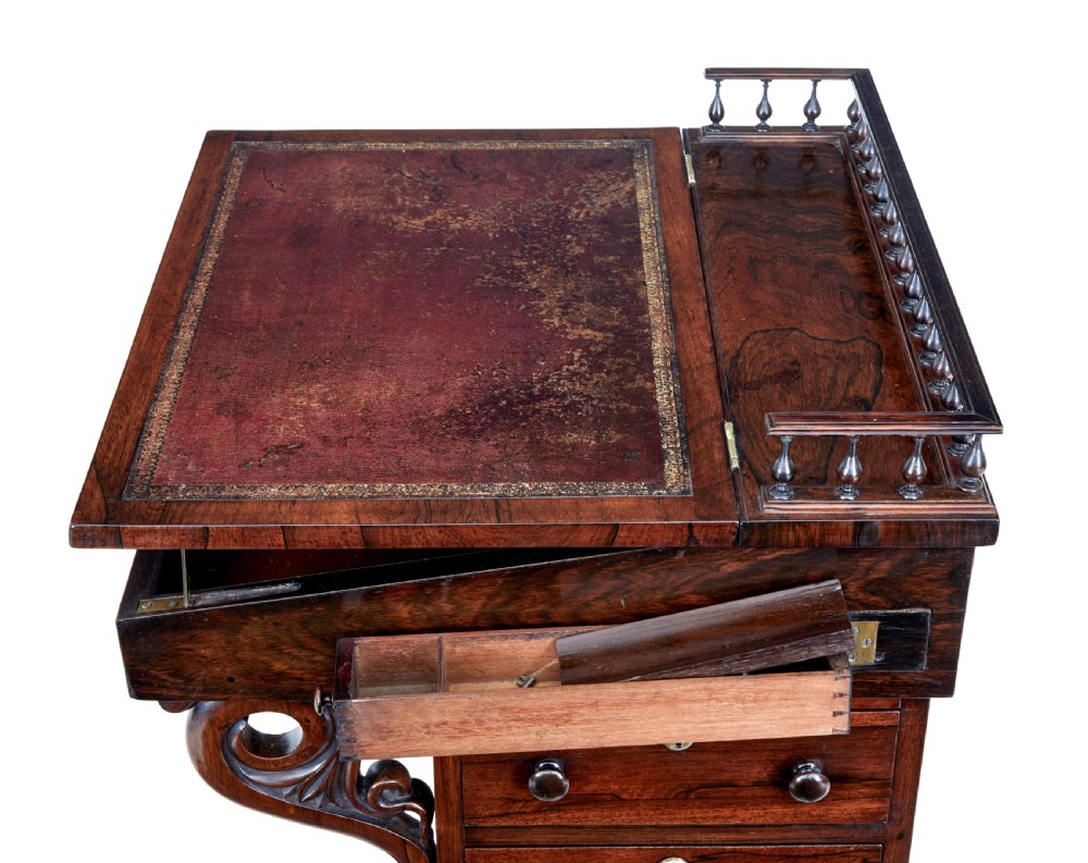 A 19th-century Regency palisander Davenport desk featuring a sloped leather writing top, carved scroll brackets, side drawers, and a brass spindle top gallery. View V