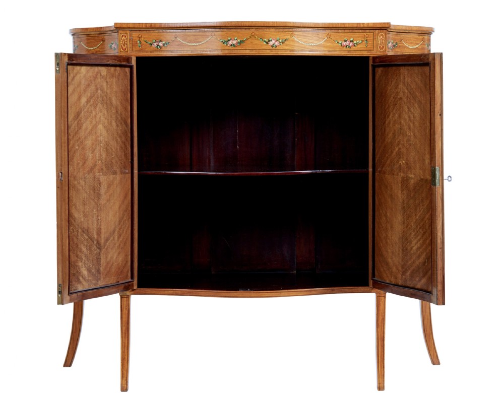 A late 19th-century Sheraton Revival satinwood cabinet featuring hand-painted floral swags, classical figurative oval panels, intricate wood marquetry, and tapered legs. View II