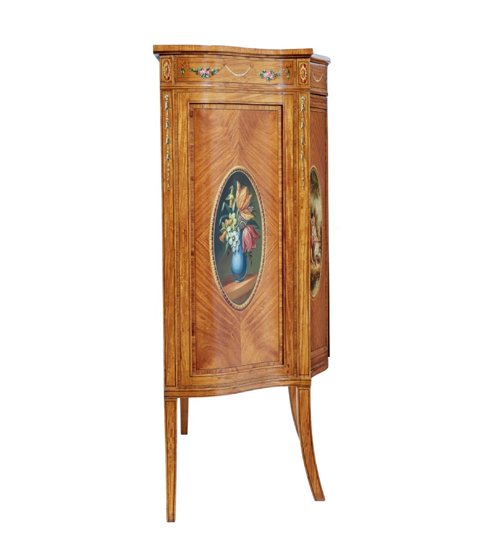 A late 19th-century Sheraton Revival satinwood cabinet featuring hand-painted floral swags, classical figurative oval panels, intricate wood marquetry, and tapered legs. View IV