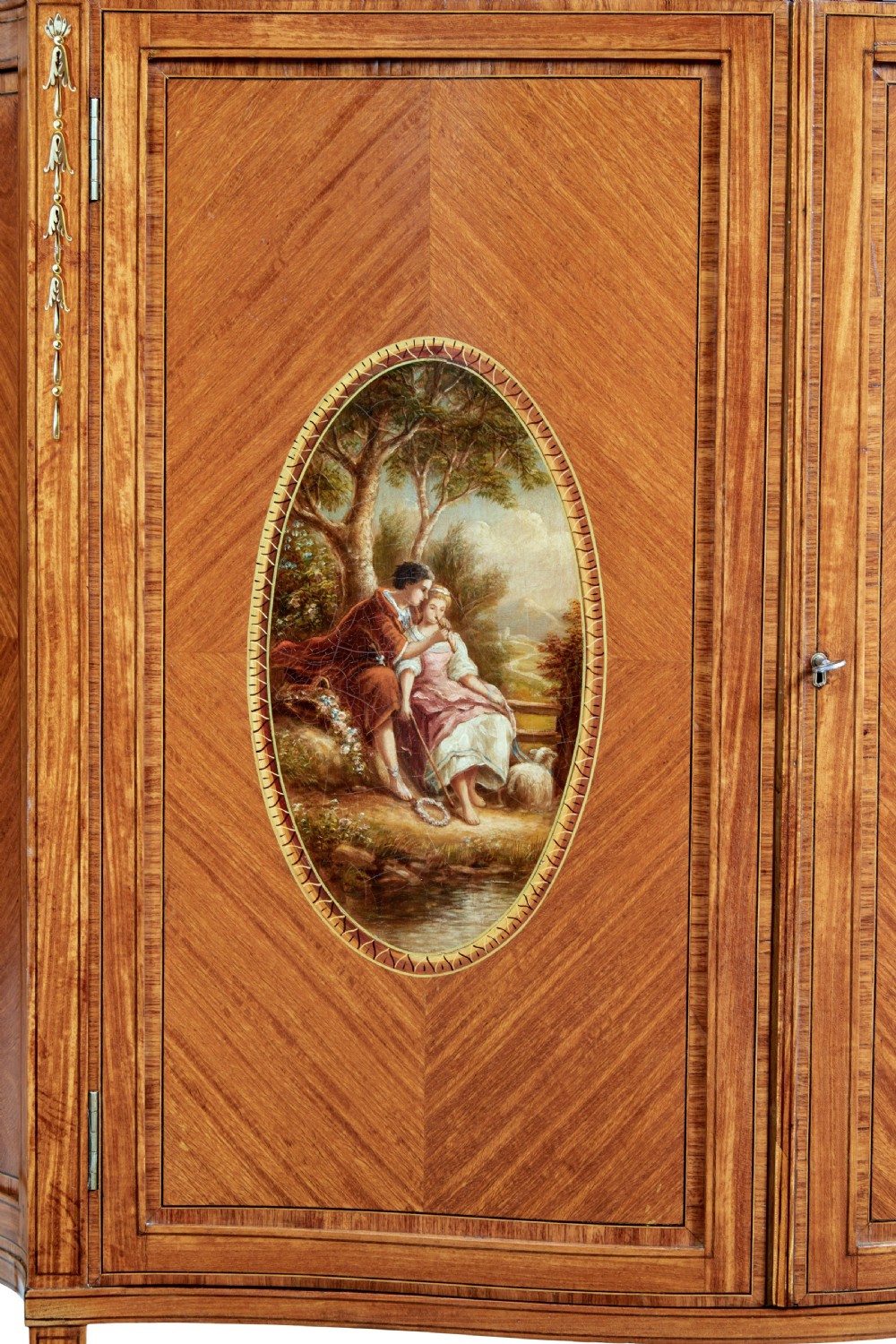 A late 19th-century Sheraton Revival satinwood cabinet featuring hand-painted floral swags, classical figurative oval panels, intricate wood marquetry, and tapered legs. View IX