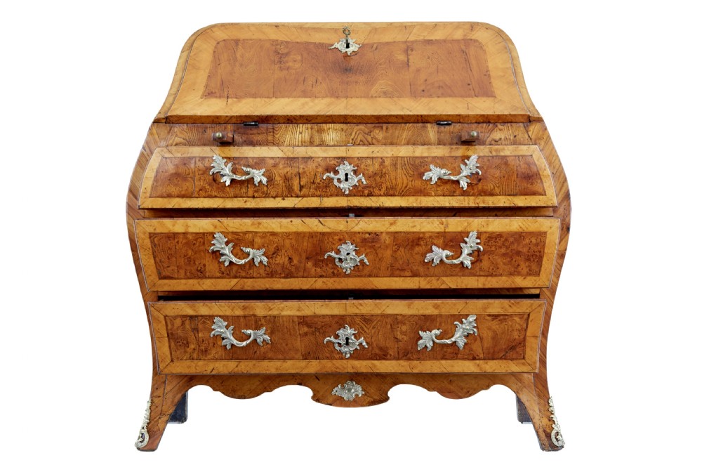 An 18th-century Rococo bureau crafted from yew and elm wood featuring a curved bombe body, slant-front writing slope, three drawers, and decorative cast brass handles. View IV