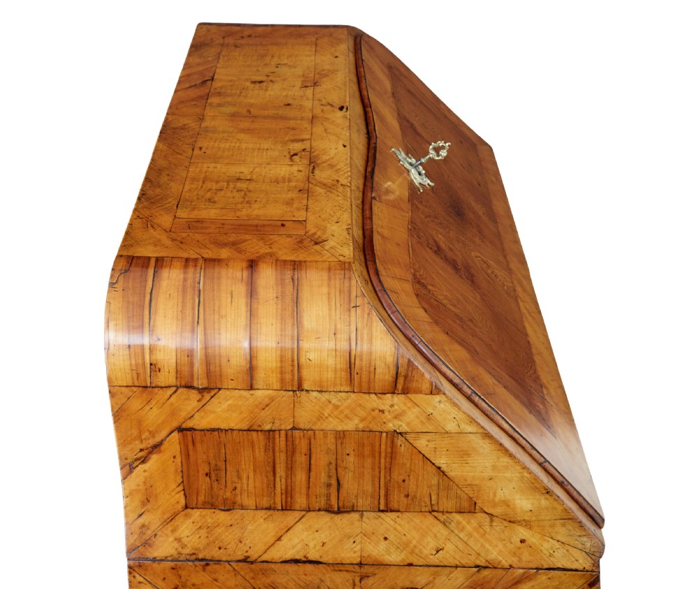 An 18th-century Rococo bureau crafted from yew and elm wood featuring a curved bombe body, slant-front writing slope, three drawers, and decorative cast brass handles. View XV
