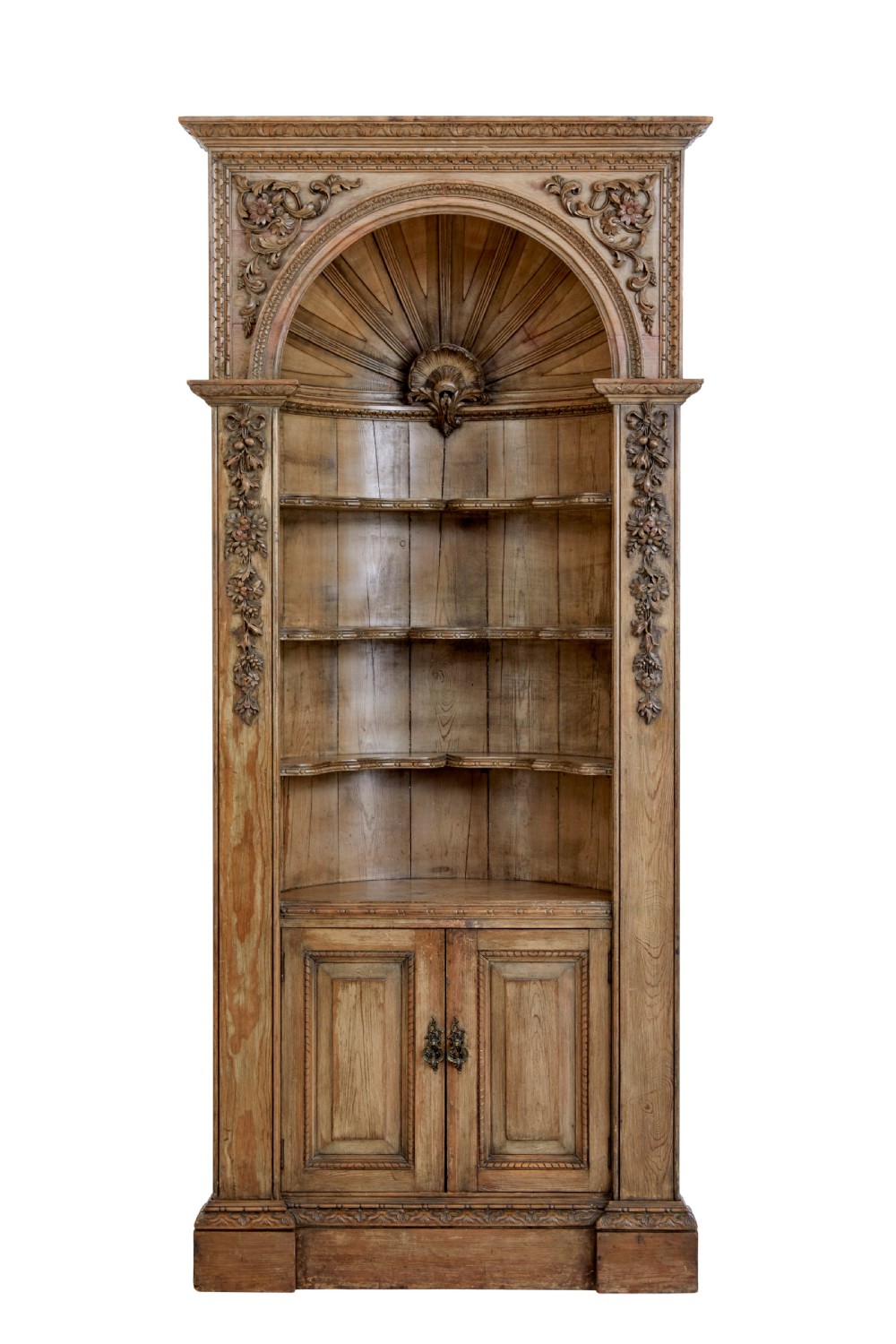 An 18th-century carved pine corner cabinet featuring a vaulted dome top with a shell carving, floral pilasters, open shelves, and a double-door base.