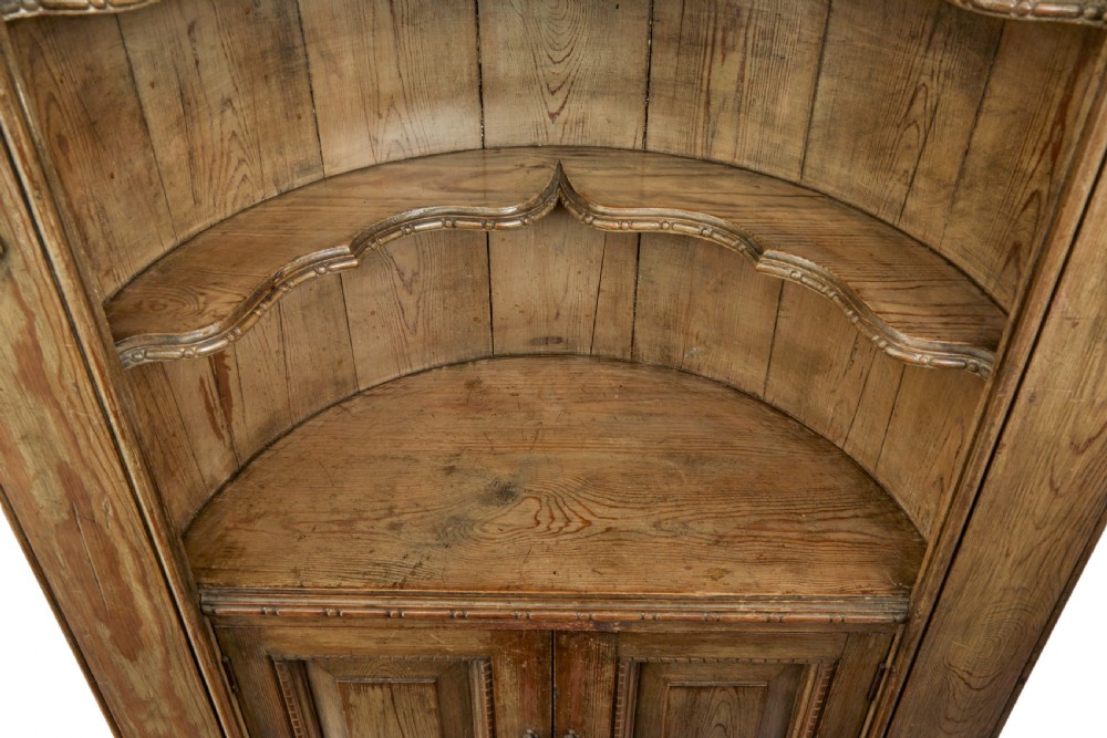 An 18th-century carved pine corner cabinet featuring a vaulted dome top with a shell carving, floral pilasters, open shelves, and a double-door base. View VI