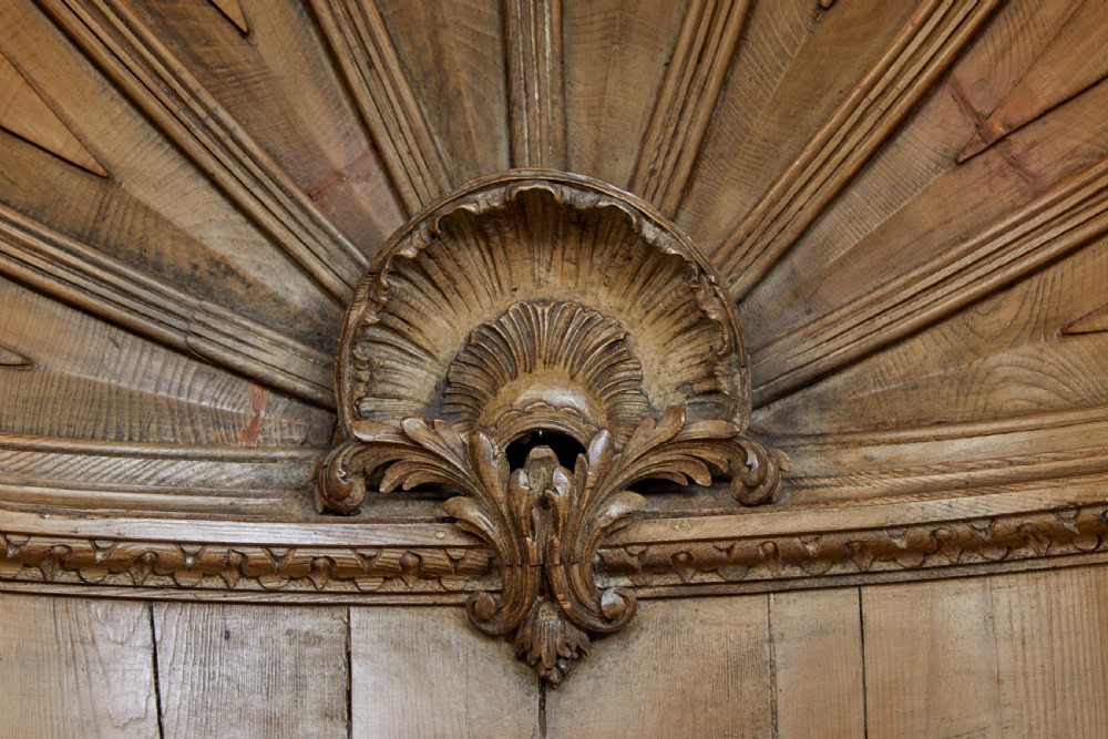An 18th-century carved pine corner cabinet featuring a vaulted dome top with a shell carving, floral pilasters, open shelves, and a double-door base. View VII
